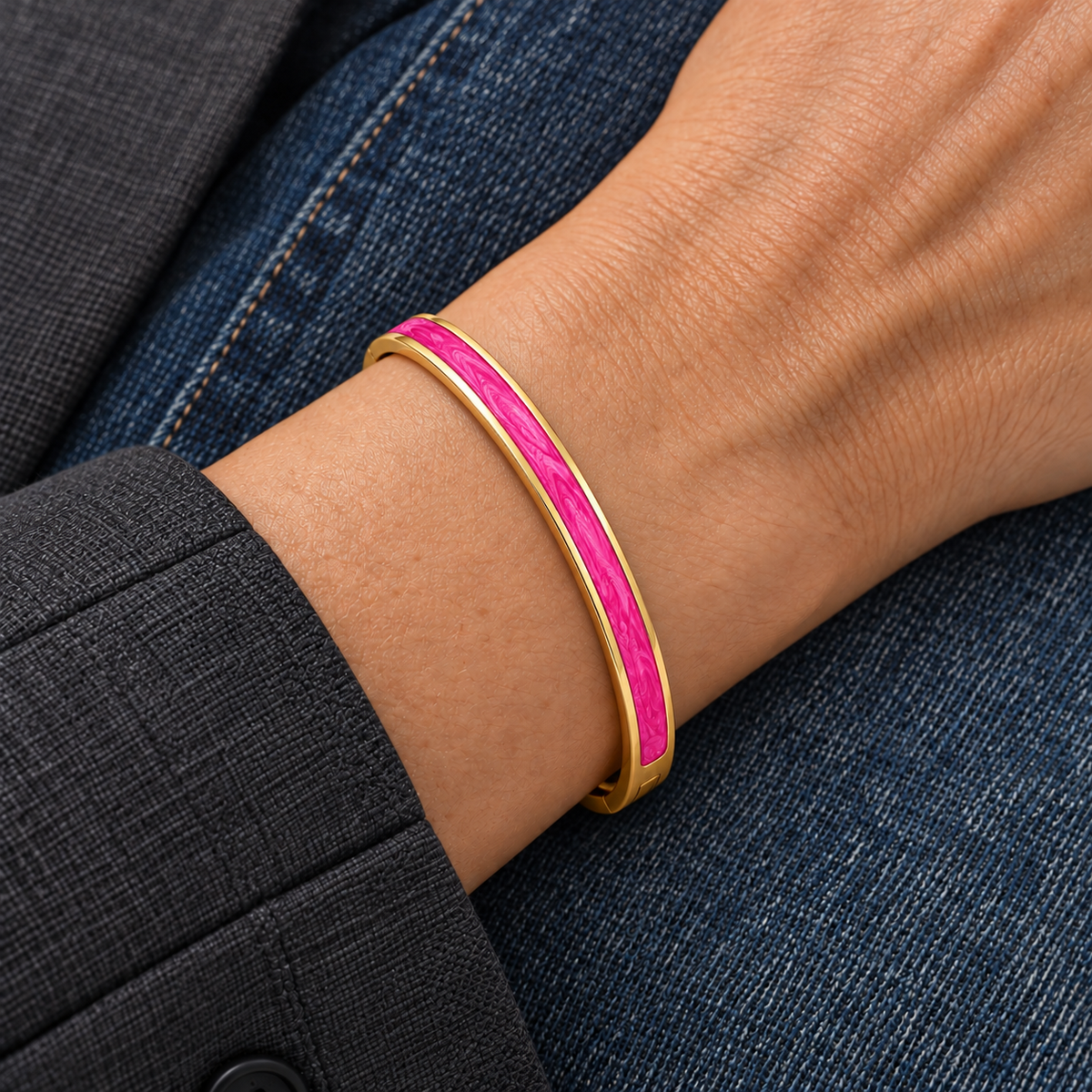 Capri Bracelet — slim pink enamel and gold bangle worn on wrist with charcoal sleeve and denim
