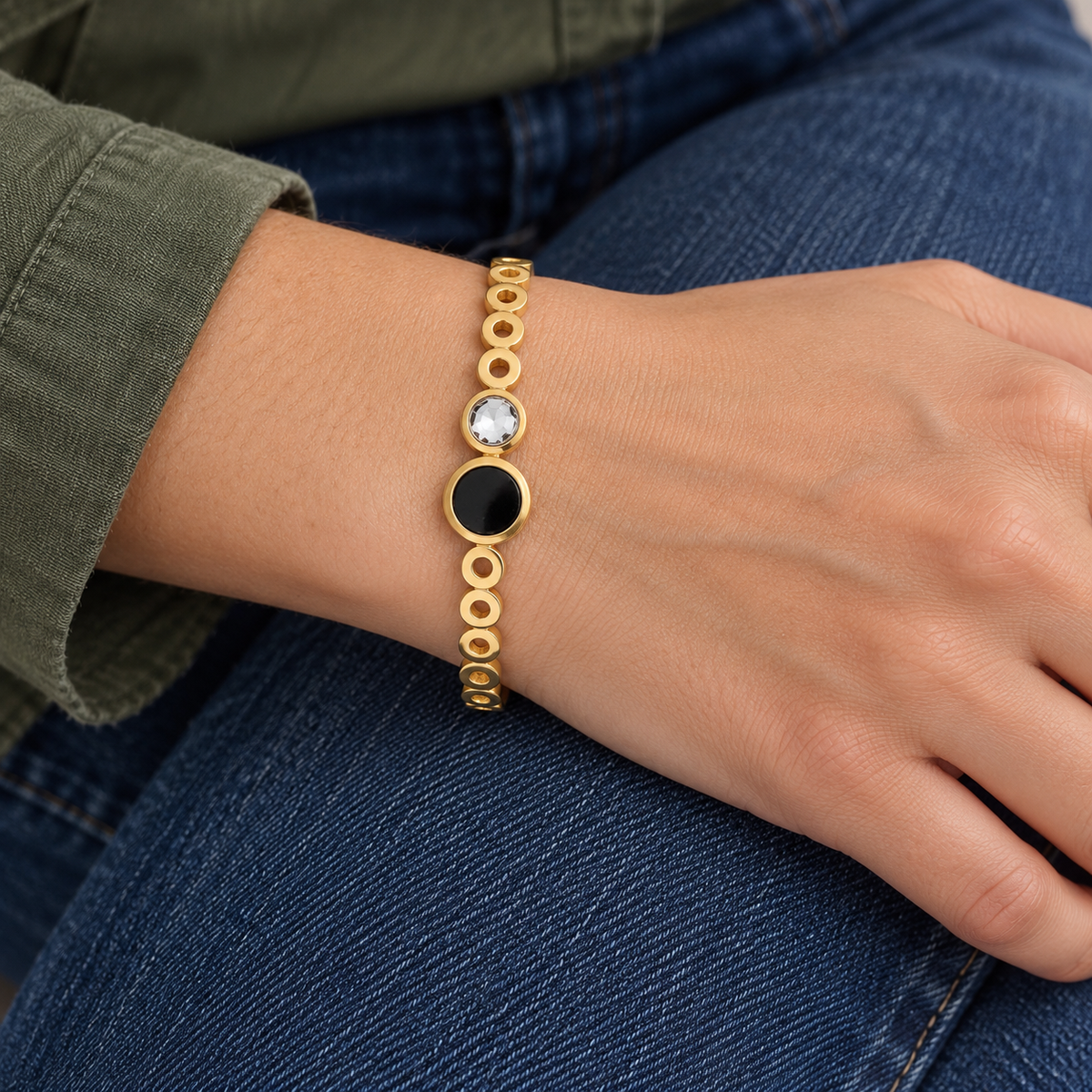 Cora Crystal Bracelet on wrist — black and clear stones joined together in one continuous gold bangle