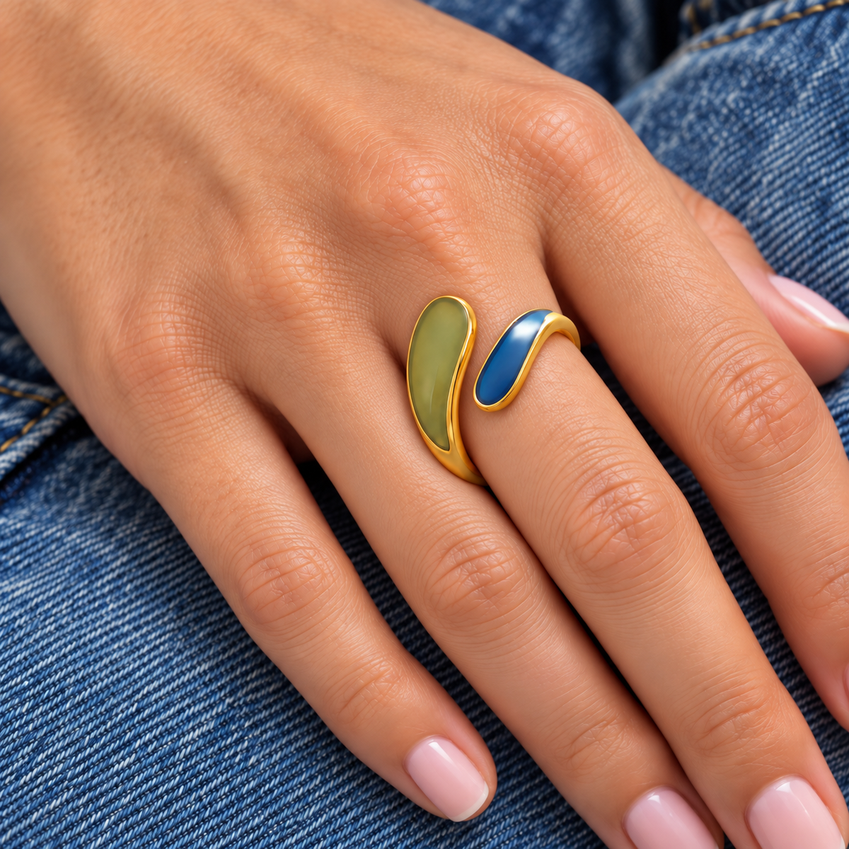Lola Ring with curved olive green and blue enamel ends worn on one finger, on denim