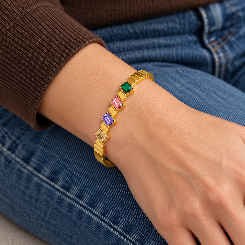 Rosalie Crystal Bracelet worn on wrist — rigid oval gold bangle with green, pink, purple and champagne rectangular crystals